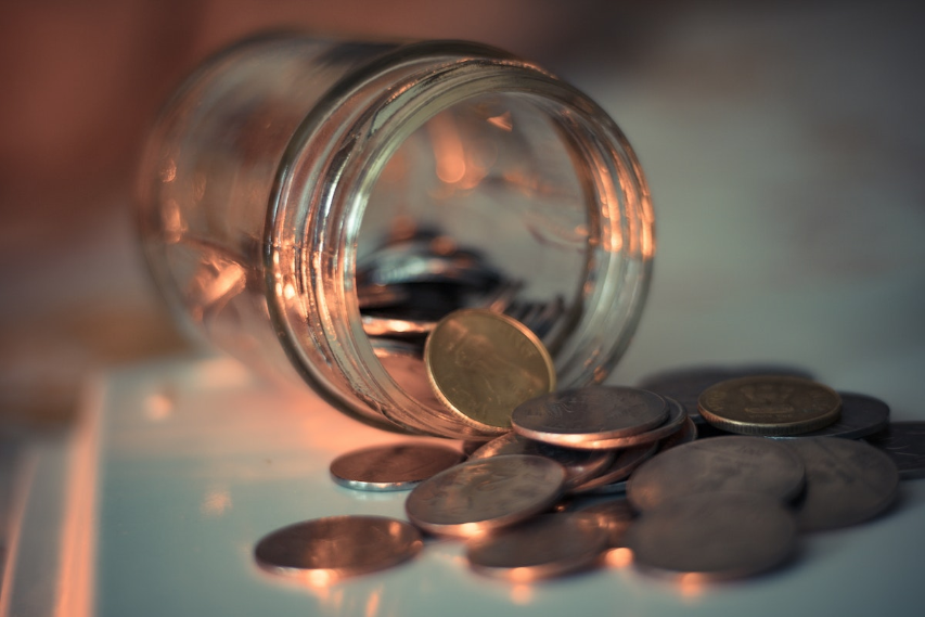 Image of a glass jar lying on its side with coins falling out