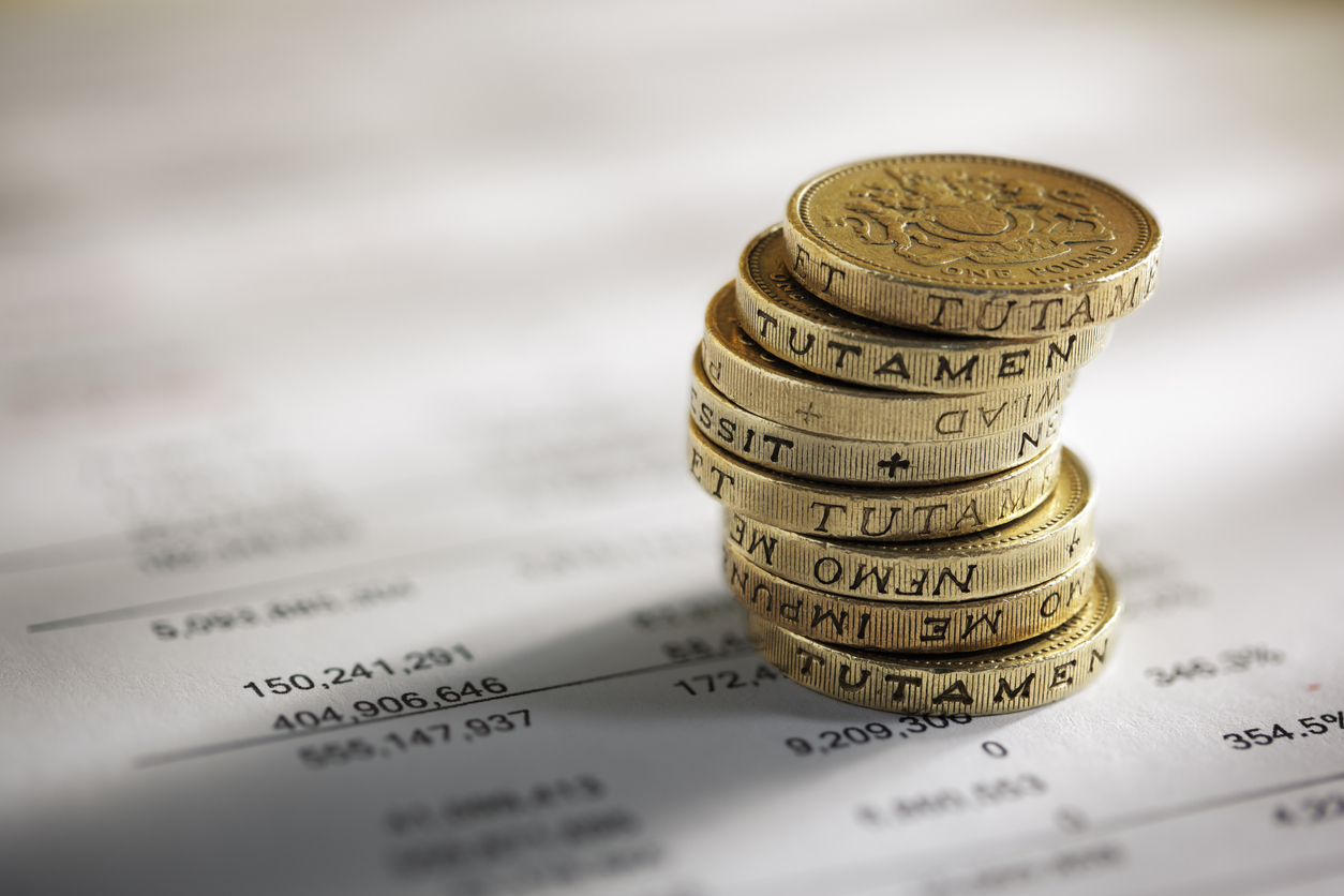 Stack of pound coins on financial figures balance sheet